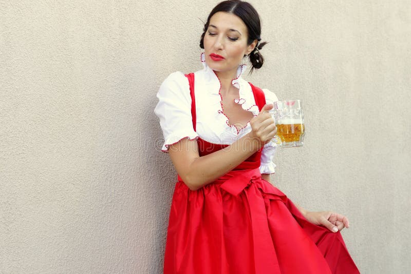 Conceito do fest de outubro Mulher alemão bonita no dirndl o mais oktoberfest típico do vestido que guarda uma caneca de cerveja imagem de stock Conceito do fest de outubro Mulher alemão bonita no dirndl o mais oktoberfest típico do vestido que guarda uma caneca de cerveja imagem de stock