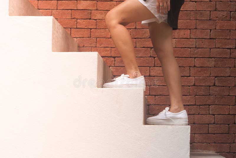 Conceito do sucesso comercial: A mulher está andando acima das escadas concretas brancas fora nas construções com fundo alaranjad fotos de stock royalty free Conceito do sucesso comercial: A mulher está andando acima das escadas concretas brancas fora nas construções com fundo alaranjad fotos de stock royalty free