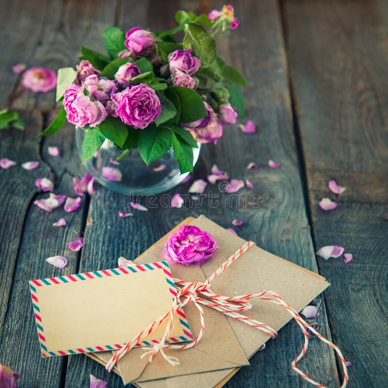 Conceito do vintage - ramalhete de murchar rosas de chá no vaso, pilha de letras velhas nos envelopes e cartão vazio no de madeir foto de stock royalty free Conceito do vintage - ramalhete de murchar rosas de chá no vaso, pilha de letras velhas nos envelopes e cartão vazio no de madeir foto de stock royalty free