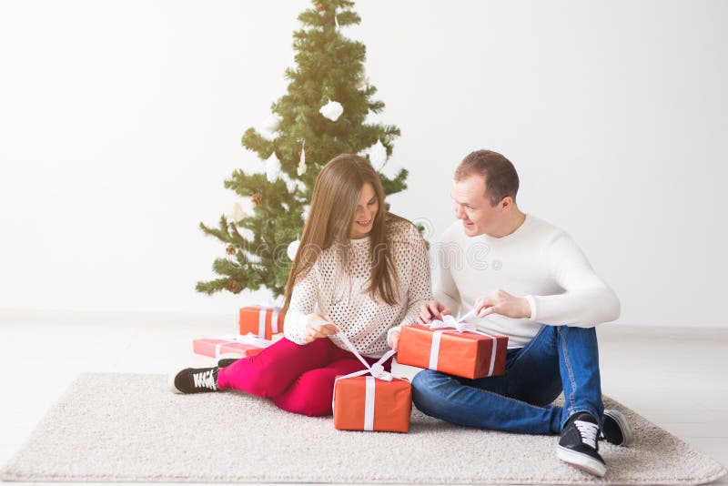 Conceito dos feriados e do Natal - presentes de abertura de sorriso do Natal dos pares novos modernos imagens de stock Conceito dos feriados e do Natal - presentes de abertura de sorriso do Natal dos pares novos modernos imagens de stock
