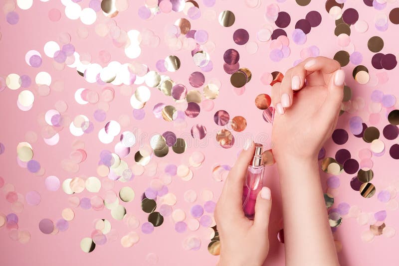 Conceito luxuoso do perfume Mãos fêmeas que guardam a garrafa à moda do perfume no fundo cor-de-rosa pastel com círculo colorido fotos de stock Conceito luxuoso do perfume Mãos fêmeas que guardam a garrafa à moda do perfume no fundo cor-de-rosa pastel com círculo colorido fotos de stock
