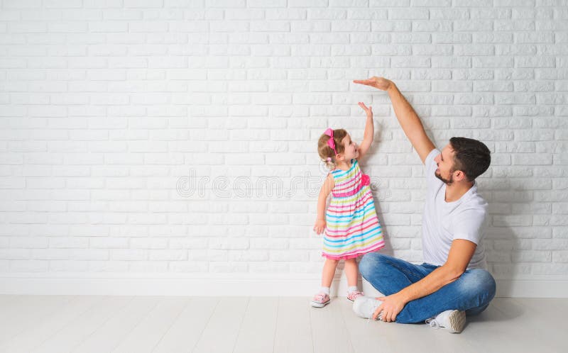 Conceito O paizinho mede o crescimento de sua filha da criança em uma parede fotos de stock Conceito O paizinho mede o crescimento de sua filha da criança em uma parede fotos de stock