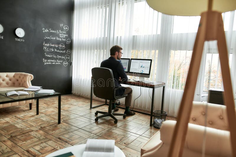Concentrated businessman, financial analyst or sales manager working on computer in the modern office, analyzing stock photography