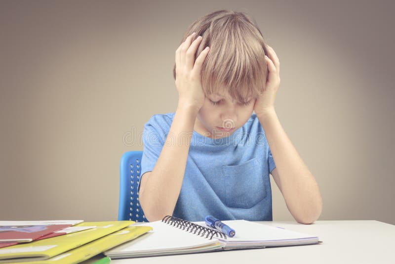 Concentrated child doing his homework at home. The boy sitting and looking in to books and notebooks. stock photos Concentrated child doing his homework at home. The boy sitting and looking in to books and notebooks. stock photos