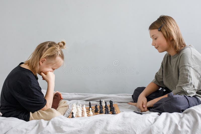 Concentrated clever children with board game having fun. Two cute children playing chess at home royalty free stock photo