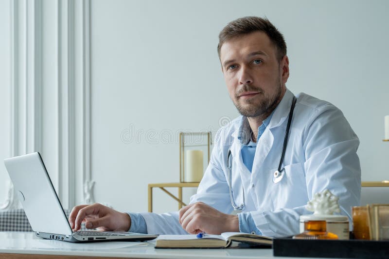 Concentrated Doctor Working With Laptop At Desk In Office Male Doctor