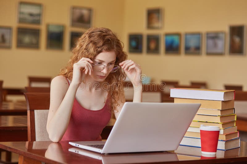 Concentrated female student study in school library, using laptop and searching for informations,using wireless internet, woman