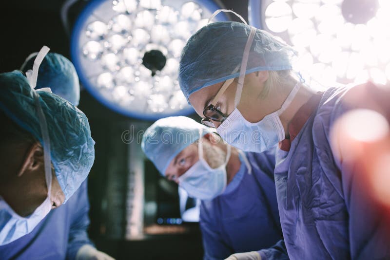 Concentrated surgeon performing surgery with her team