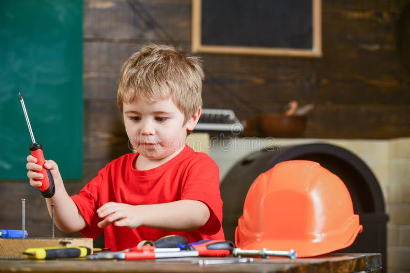 Concentrated kid playing with screwdriver. Cute blond boy learning to work with tools. Little repairman grabbing