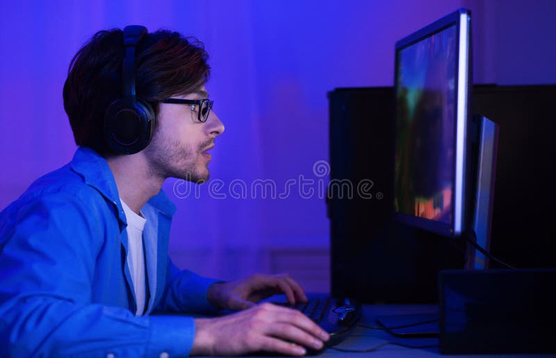 Gamer Taking Part In Online Tournamet Sitting At Computer Indoor royalty free stock photo Gamer Taking Part In Online Tournamet Sitting At Computer Indoor royalty free stock photo