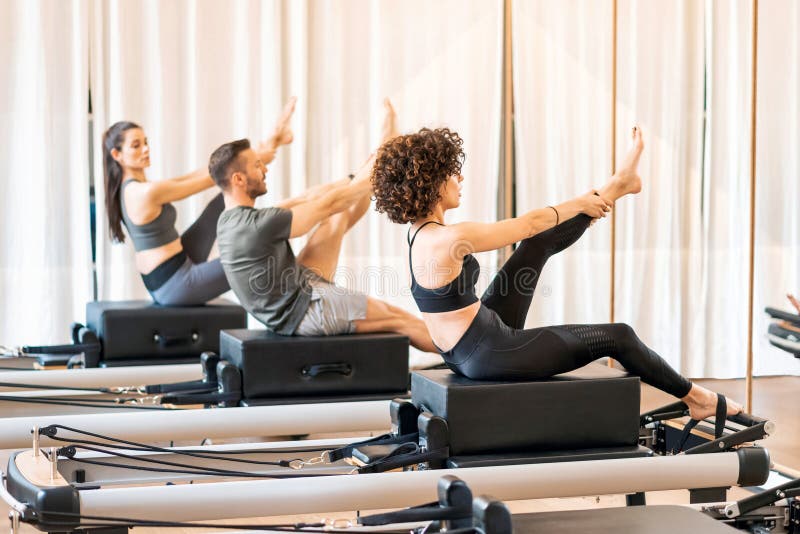 Concentrated fit female stretching legs and doing lunge exercises on pilates  reformer during training in gym stock photo