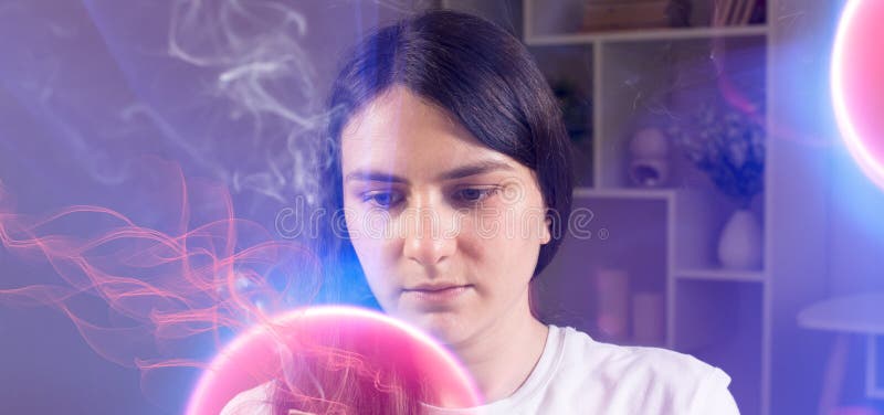 A concentrated woman looks at the pink burning ball. Quantum theory of man, consciousness and physics.