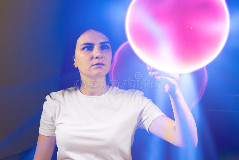 A concentrated woman looks at the pink burning ball. Quantum theory of man, consciousness and physics.