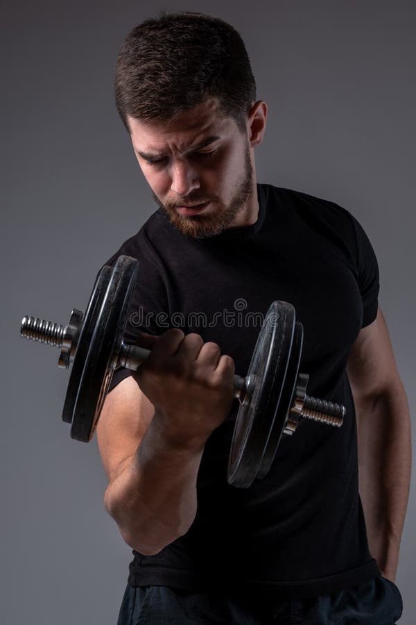 Concentrated Young Man Performing Bicep Curl With Dumbbell Stock Image