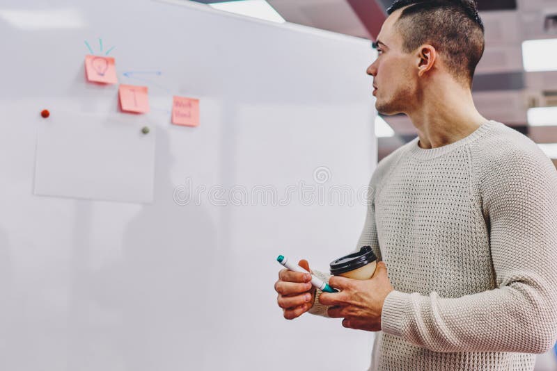 Student la hipster pensiv îmbrăcat în uzură ocazională, verificând informațiile scrise la bord royalty free stock photos