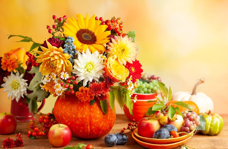Concept of autumn festive decoration for Thanksgiving day. Autumn bouquet of flowers and berries in a pumpkin on a table, different fruits and pumpkins..