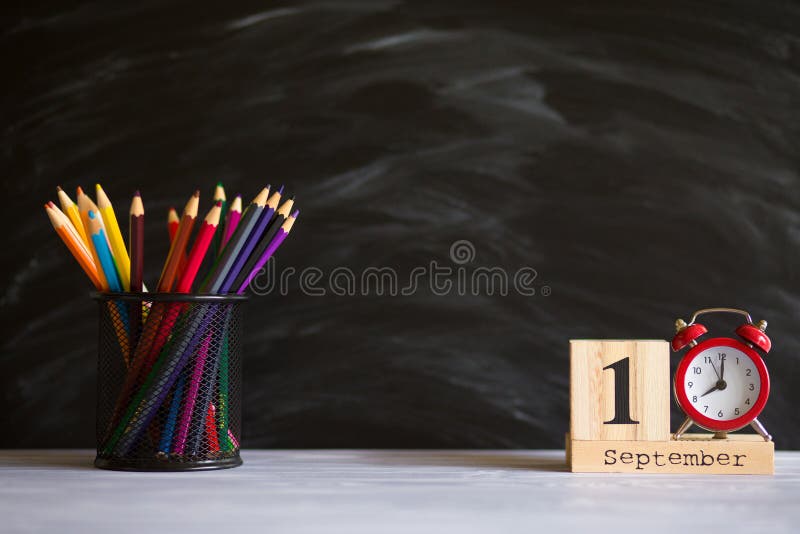 Concept back to school. Red alarm clock with color pencils and wooden calendar set on 1st september on blackboard background. stock photography Concept back to school. Red alarm clock with color pencils and wooden calendar set on 1st september on blackboard background. stock photography