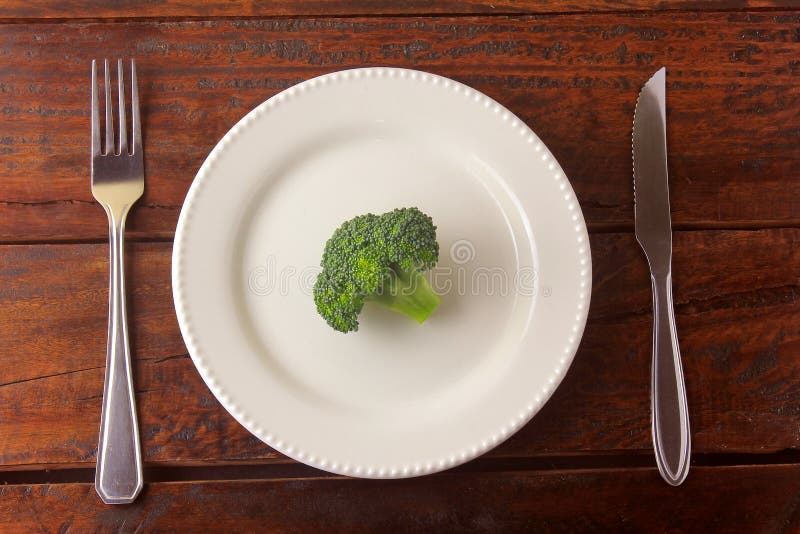 Concept of calorie restriction. Strict diet. Sliced pod isolated on white plate with fork and knife