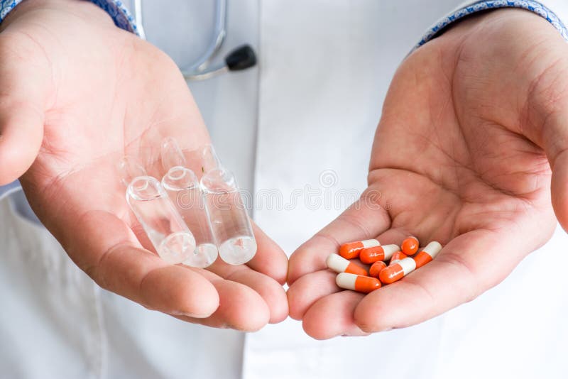 Concept of choice of therapeutic treatment - orange capsules with medication or injectable therapy in form of ampoules with medici