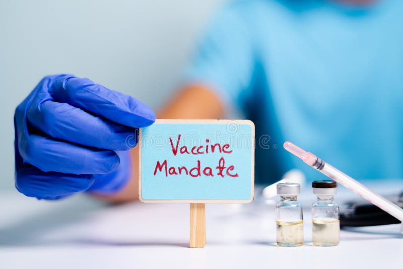 Concept of coronavirus or covid-19 vaccine mandate, showing with doctor hands with gloves by placing sign board next to vaccine