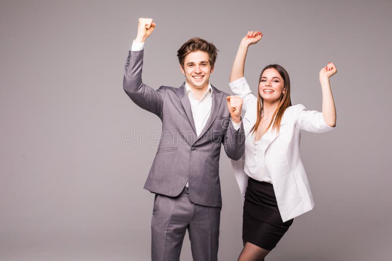 Concept d'association dans les affaires Jeune homme et femme se tenant avec les mains augmentées sur le fond gris Émotions de gai photo stock Concept d'association dans les affaires Jeune homme et femme se tenant avec les mains augmentées sur le fond gris Émotions de gai photo stock