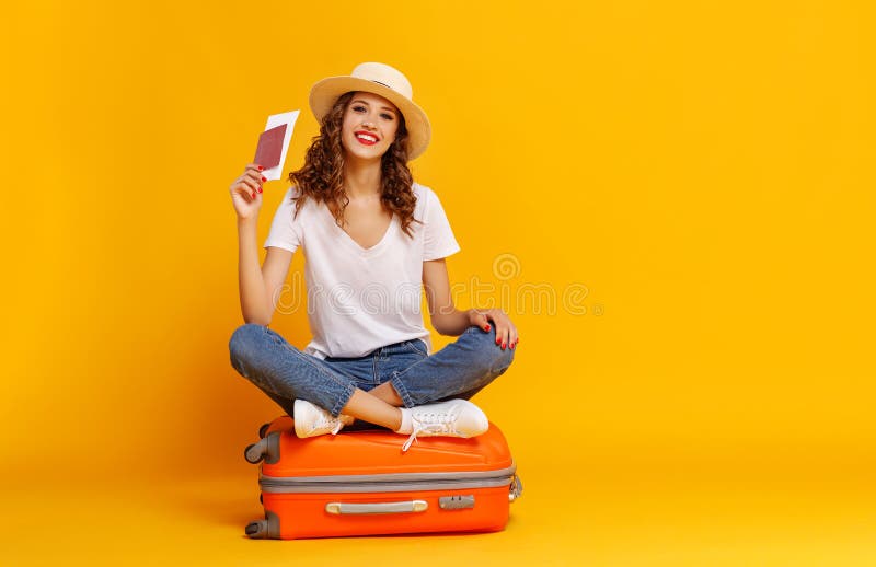 Concept of travel. happy woman girl with suitcase and passport on  yellow colored background. Concept of travel. happy woman girl with suitcase and passport on  yellow colored background