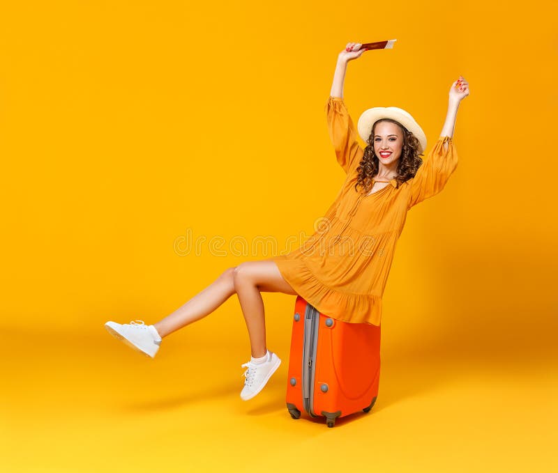 Concept de course fille heureuse de femme avec la valise et passeport sur le fond jaune photo stock Concept de course fille heureuse de femme avec la valise et passeport sur le fond jaune photo stock