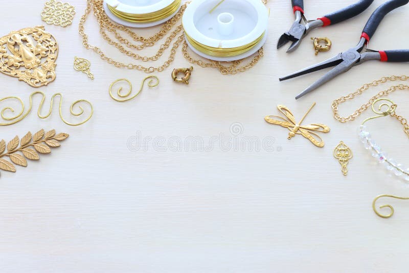 Concept de fabricare a bijuteriilor cu caractere filigranate cu lanț auriu și instrumente pe fond alb din lemn royalty free stock image