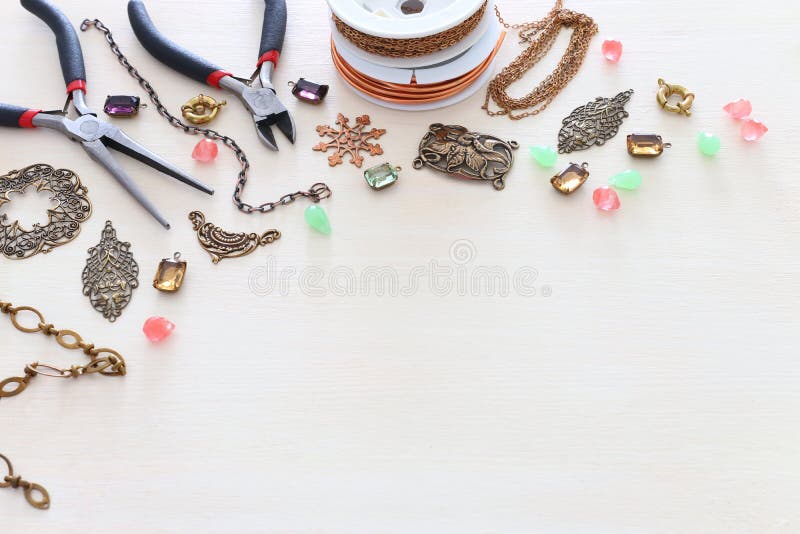 Concept de fabricare a bijuteriilor cu caracteristici de filigran cu lanț din alamă și instrumente pe fond alb din lemn stock photography