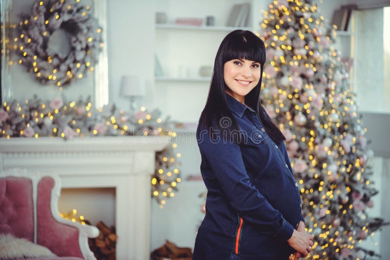 Concept de grossesse, d'amour, de personnes et d'attentes - la femme enceinte heureuse, se tient dans une chambre dans la perspec image stock Concept de grossesse, d'amour, de personnes et d'attentes - la femme enceinte heureuse, se tient dans une chambre dans la perspec image stock