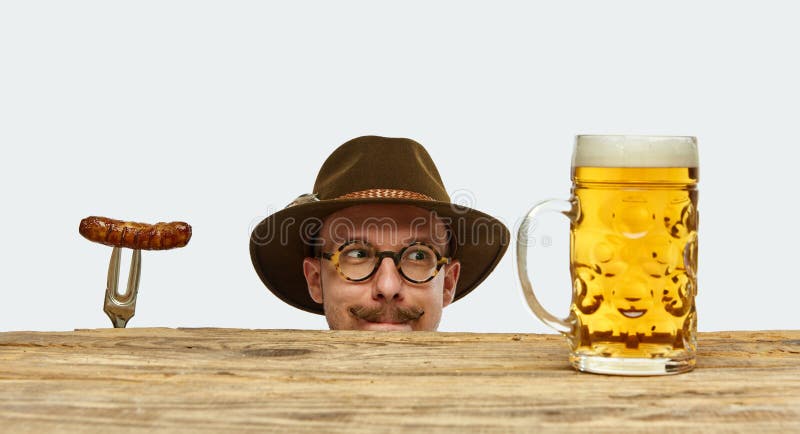 Slyly man wearing traditional fest Bavarian or German outfit with huge beer mug and fried sausage celebrating Oktoberfest. Concept of Oktoberfest, traditions, drinks and food. Copy space for ad. Slyly man wearing traditional fest Bavarian or German outfit with huge beer mug and fried sausage celebrating Oktoberfest. Concept of Oktoberfest, traditions, drinks and food. Copy space for ad