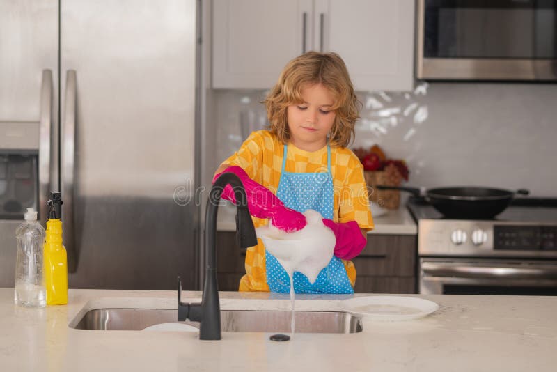 Une Petite Fille Essuie La Vaisselle Dans La Cuisine. Bébé Fait Des Travaux  Ménagers à La Maison.