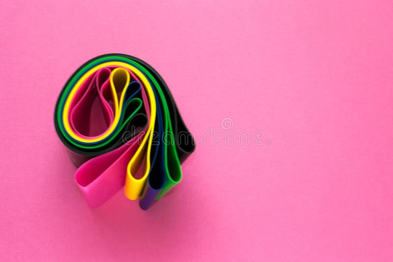 Concept de sport - a roulé l'ensemble d'extenseurs élastiques de forme physique colorée pour la femme sur le fond rose Mode de vi photos stock Concept de sport - a roulé l'ensemble d'extenseurs élastiques de forme physique colorée pour la femme sur le fond rose Mode de vi photos stock