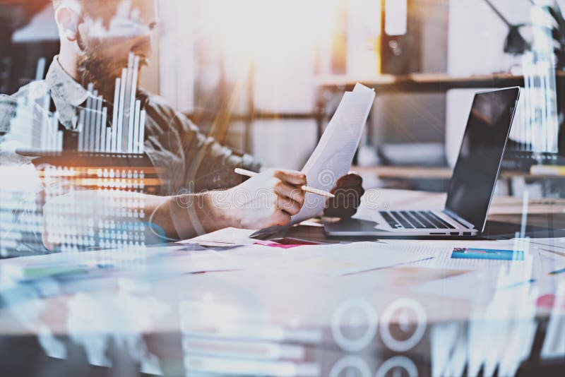 Concept of digital diagram,graph interfaces,virtual screen,connections icon.Young entrepreneur working at modern office with paper document.Man using contemporary laptop,blurred background.Horizontal