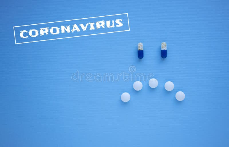 2019 Novel Coronavirus 2019-nCoV concept. Sad smiley face made of blue and white tablets and pills on blue background top view with stamp: Coronavirus and copy space for your text. 2019 Novel Coronavirus 2019-nCoV concept. Sad smiley face made of blue and white tablets and pills on blue background top view with stamp: Coronavirus and copy space for your text