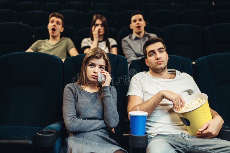 Couple with popcorn in cinema. Boring film concept, people watching movie. Couple with popcorn in cinema. Boring film concept, people watching movie