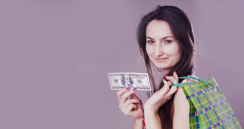 Concept: Everything has its own price. Image of a beautiful shocked happy woman with shopping bag holds US Dollar bill royalty free stock photos Concept: Everything has its own price. Image of a beautiful shocked happy woman with shopping bag holds US Dollar bill royalty free stock photos