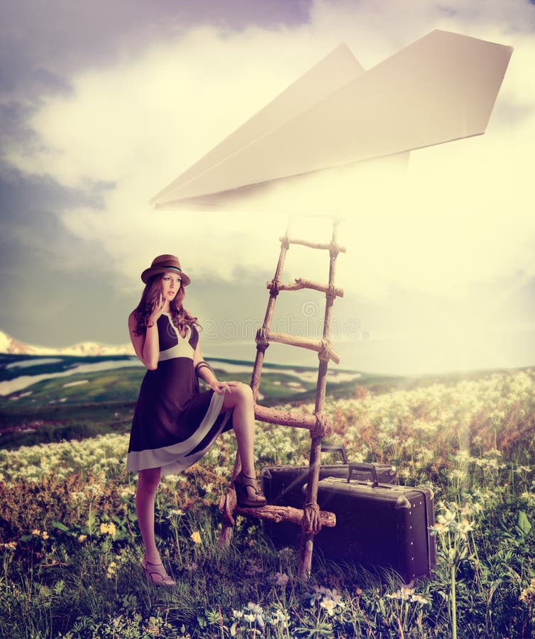Concept - dreaming about travel.Beautiful woman with suitcases standing near the ladder to the paper plane in the clouds. Concept - dreaming about travel.Beautiful woman with suitcases standing near the ladder to the paper plane in the clouds