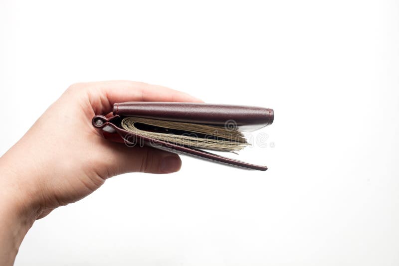 Female hand holds closed brown wallet with a thick wad of bills. isolated over a white background stock photos Female hand holds closed brown wallet with a thick wad of bills. isolated over a white background stock photos
