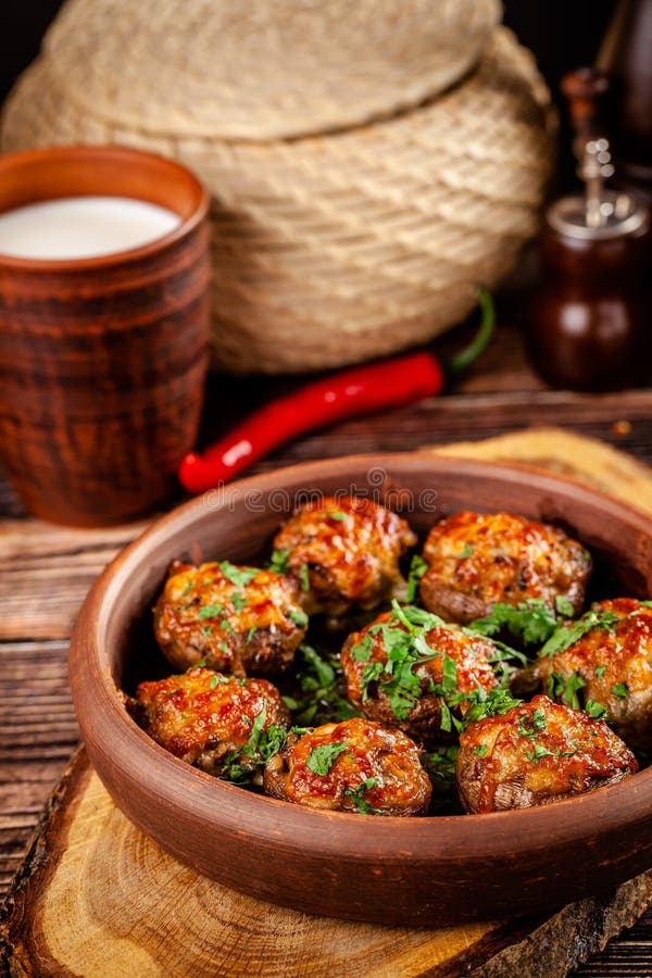 The concept of Georgian cuisine. Baked mushrooms champignons with meat and cilantro. Serving dishes in a restaurant in a plate