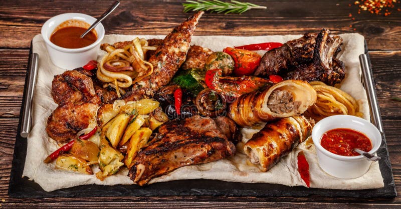 Concept of Georgian cuisine. Large meat board with shashlik, roasted meat, french fries, roast lamb and sauce. Serving dishes