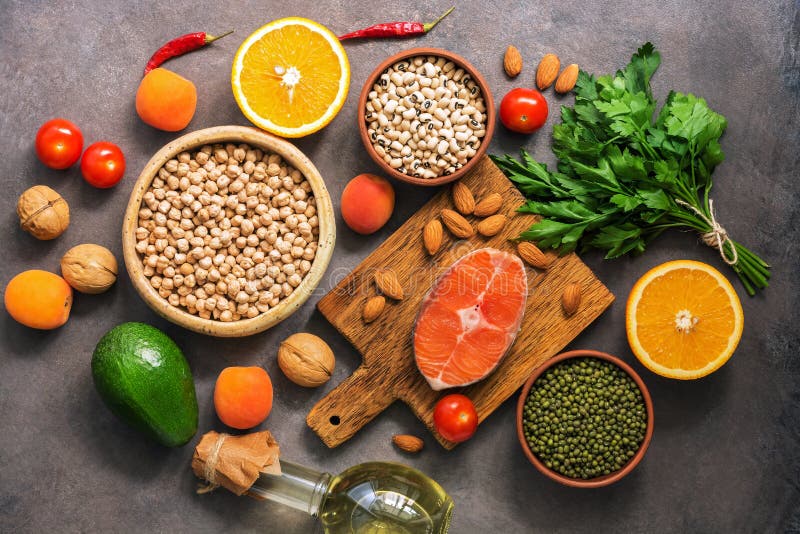Concept healthy balanced food, salmon,legumes, fruits, vegetables, olive oil and nuts, dark rustic background. Flat lay, top view royalty free stock photography Concept healthy balanced food, salmon,legumes, fruits, vegetables, olive oil and nuts, dark rustic background. Flat lay, top view royalty free stock photography