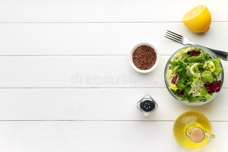 Concept of healthy food. Fresh salad in bowl with flax seed on white wooden table.