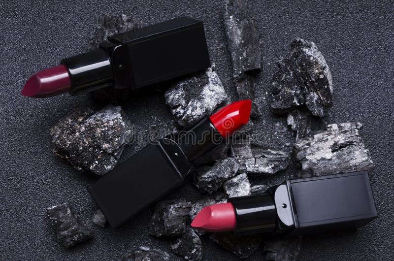 Concept of hot sale of cosmetics.Red and pink lipsticks on the dark charcoal royalty free stock images Concept of hot sale of cosmetics.Red and pink lipsticks on the dark charcoal royalty free stock images