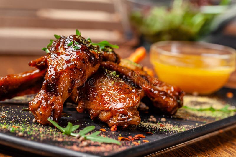 The concept of Indian cuisine. Baked chicken wings and legs in honey mustard sauce. Serving dishes in the restaurant