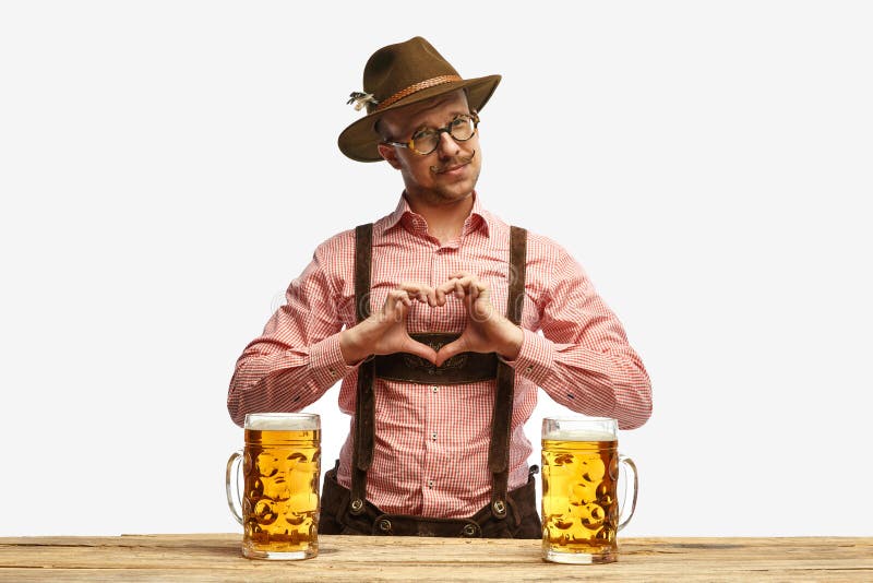 I love beer festival. Man with mustaches wearing traditional german outfit showing heart symbol shape feelings on holiday event. Concept of Oktoberfest, traditions, drinks and food. Copy space for ad