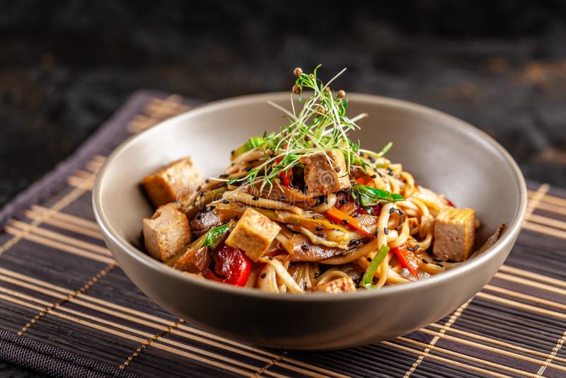 The concept of Japanese cuisine. Chinese noodles with chicken, grilled vegetables, and tofu in unagi sauce. Serving Asian dishes