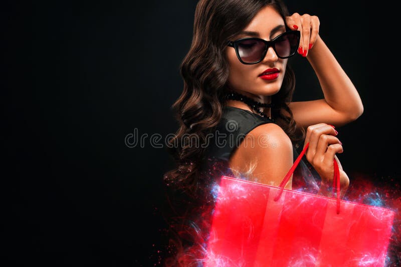 Concept noir de vente de vendredi Femme d'achats jugeant le sac rouge d'isolement sur le fond fonc? dans les vacances image stock Concept noir de vente de vendredi Femme d'achats jugeant le sac rouge d'isolement sur le fond fonc? dans les vacances image stock