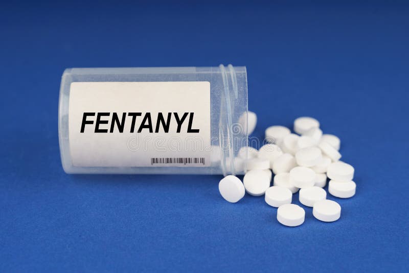On a blue surface are pills and a dusty jar with the inscription - Fentanyl