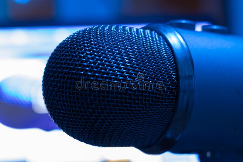 Concept of podcast or broadcasting radio. Pro condenser mic with blurry background with laptop. Blue light royalty free stock photo